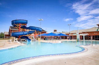 A blue spiral-like water slide stands by a swimming pool at the Wackford Aquatic Complex.